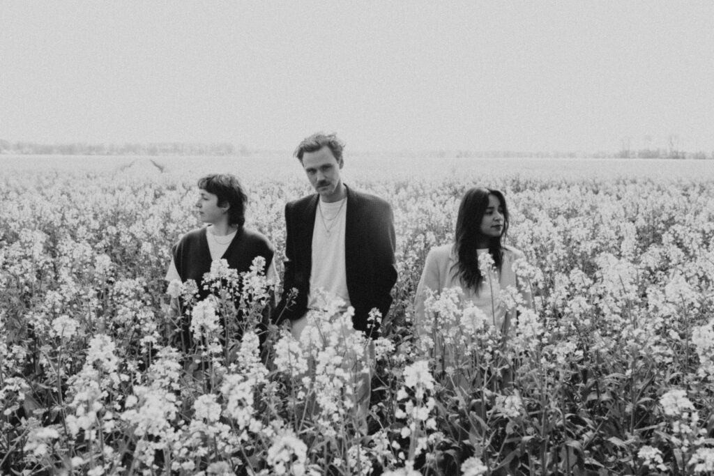 Schwarz-weiß Bild von Jules Ahoi und zwei weiteren Personen in einem Rapsfeld