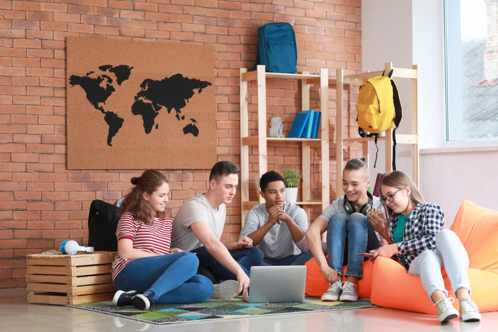 Gruppe Jugendlicher verbringen gemeinsam Zeit miteinander, sitzend auf dem Boden und Sitzsäcken., Link auf AngebotAngebote für Kinder und Jugendliche - Stadt Kölne für Kinder und Jugendliche