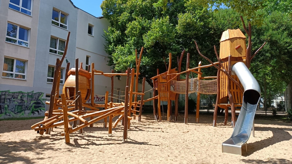 Spielplatz Buschgasse/An der Eiche. Zu sehen sind Spielgeräte und eine Rutsche.