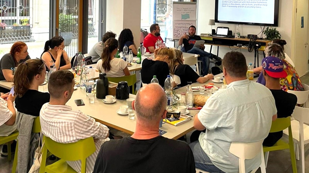 Gruppe von Fachkräften sitzt an Tischen und hört einem Vortrag zu., Link auf Internationale Jugendarbeit – Angebote für Fachkräfte