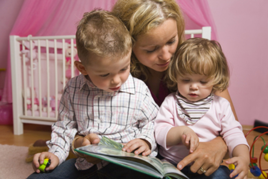 Tagesmutter mit zwei Kindern beim Vorlesen