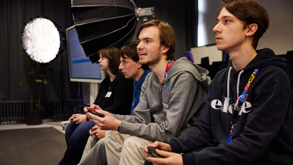 Inklusives Gaming im Rahmen von Gaming ohne Grenzen. Zu sehen sind vier Jugendliche sitzend vor einer Spielekonsole.