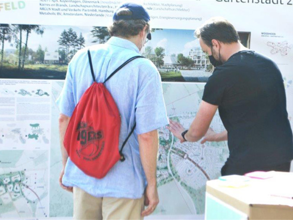 Zwei Personen sehen sich die sechs Planentwürfe zu Köln-Kreuzfeld an