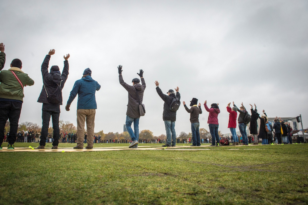 Menschen in einer Reihe, die Hände hebend