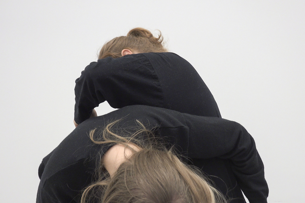 Zwei Frauen in schwarzer Kleidung übereinander gebeugt. Die Gesichter der Personen sind nicht zu erkennen. 