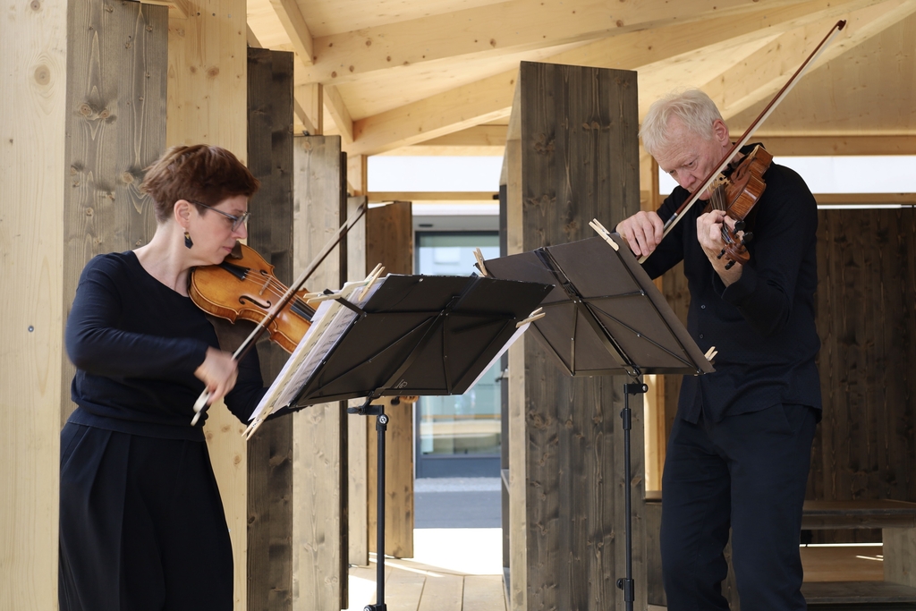 Foto von zwei Musiker*innen, die ein Streichinstrument spielen