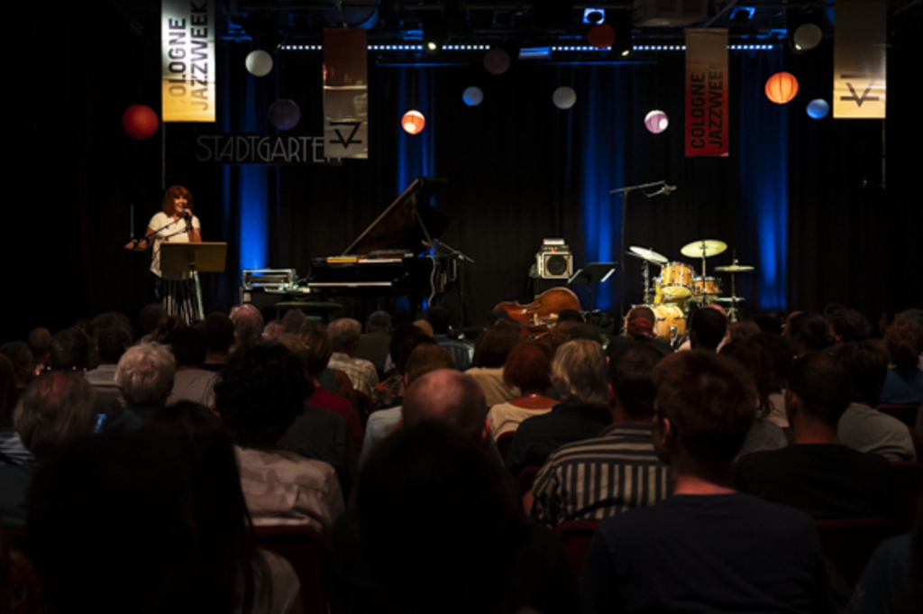 Ulla Oster heißt das Publikum im gut besuchten Saal des Stadtgartens willkommen