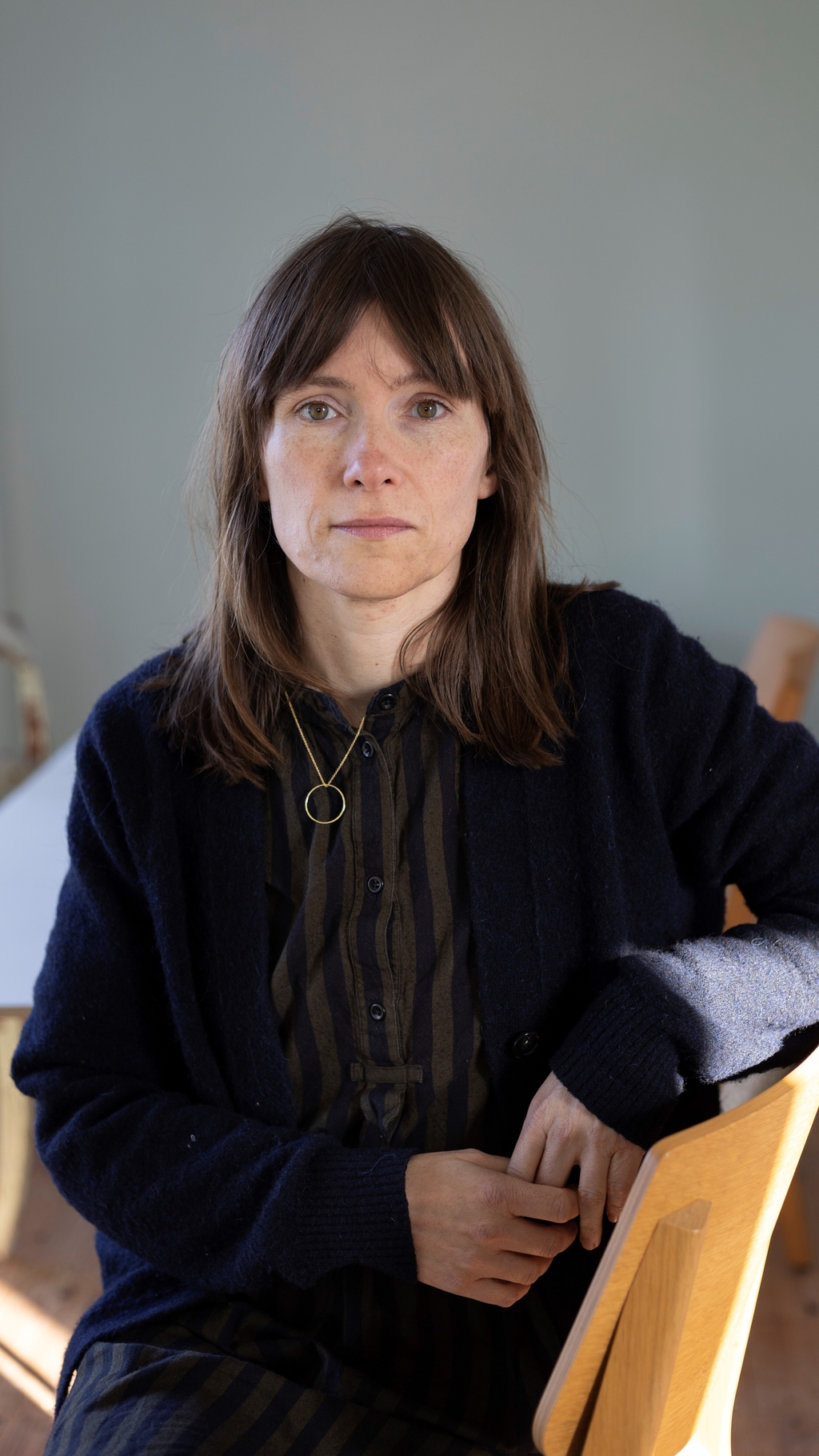 Foto von Heike Geissler. Sie sitzt auf einem Stuhl und trägt dunkle Klamotten