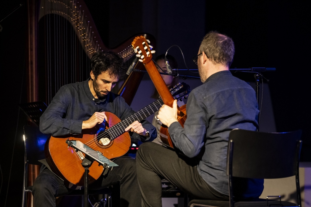 Zwei Künstler*innen mit ihren Gitarren auf der Bühne