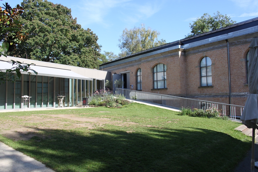 Foto des Innenhofes der Orangerie, im Vordergrund ein Rasenstück, im Hintergrund die Orangerie