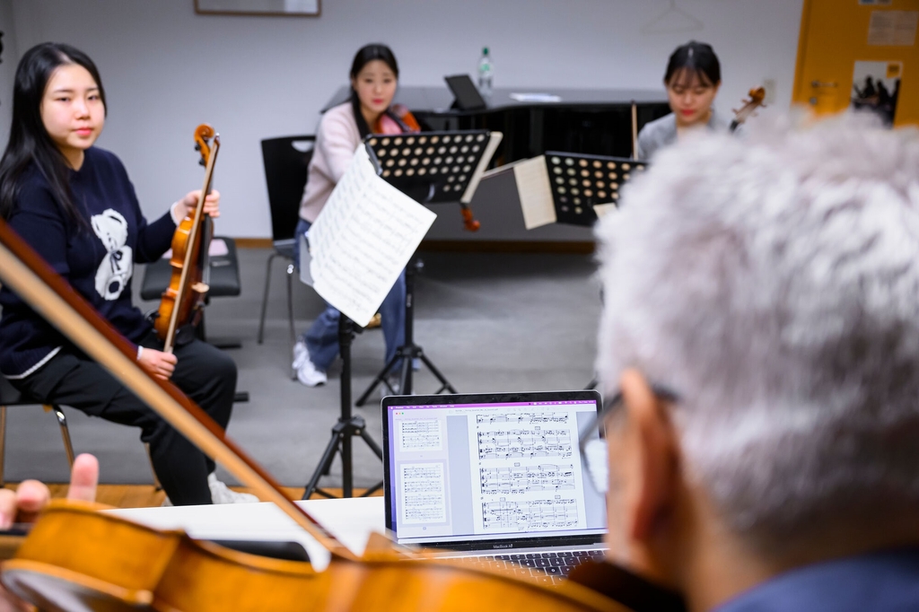 Vier Personen sitzen mit ihren Streichinstrumenten vor ihren Noten im Kreis
