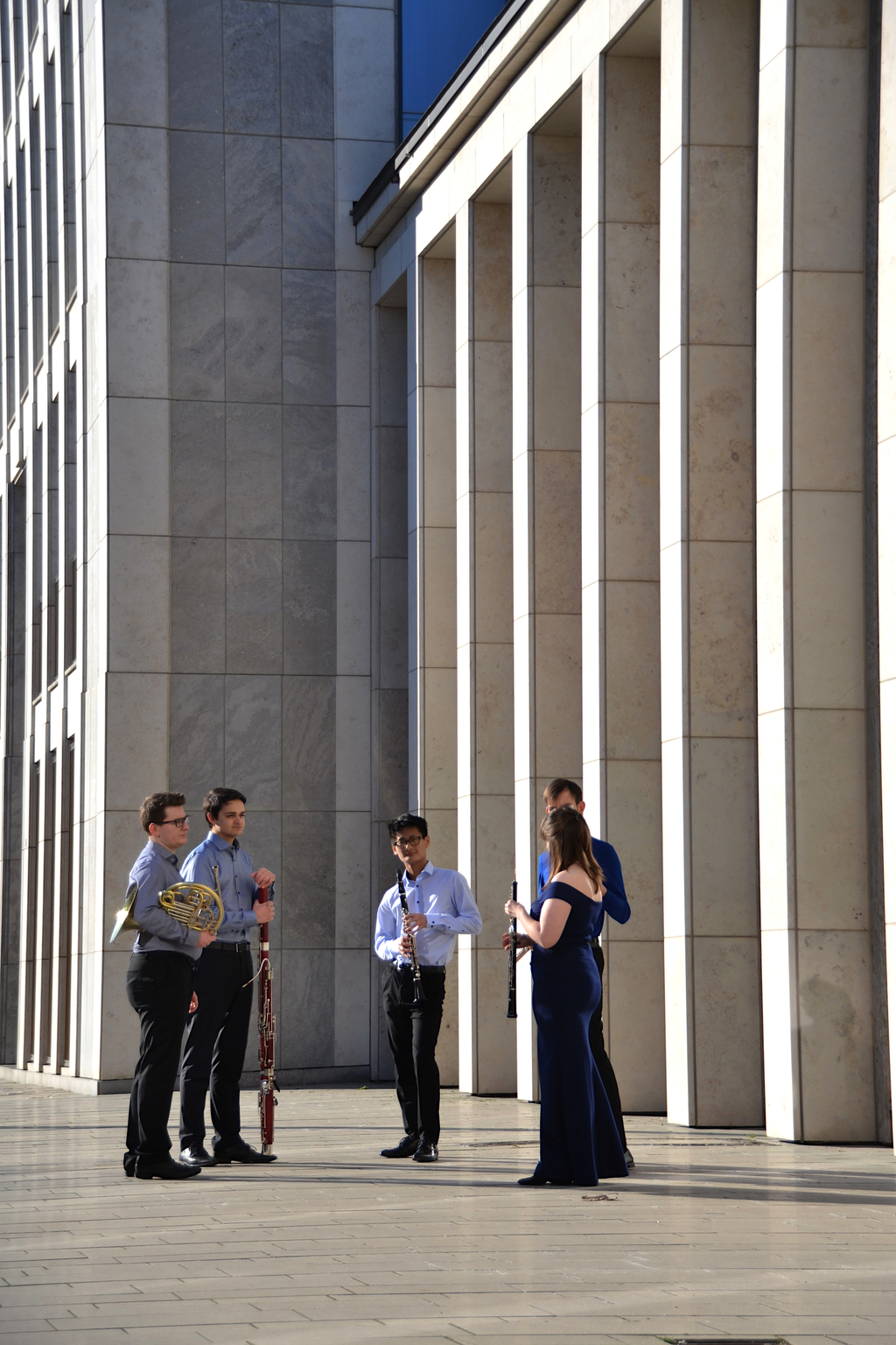 Fünf Personen stehen mit Ihren Blasinstrumenten im Kreis vor einem Gebäude