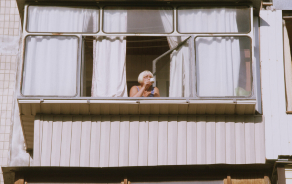 Eine Frau steht am geöffneten Fenster eines Balkons