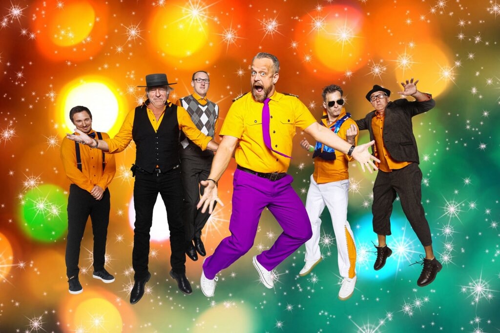 Sechs Männer in bunten Outfits vor buntem Hintergrund 