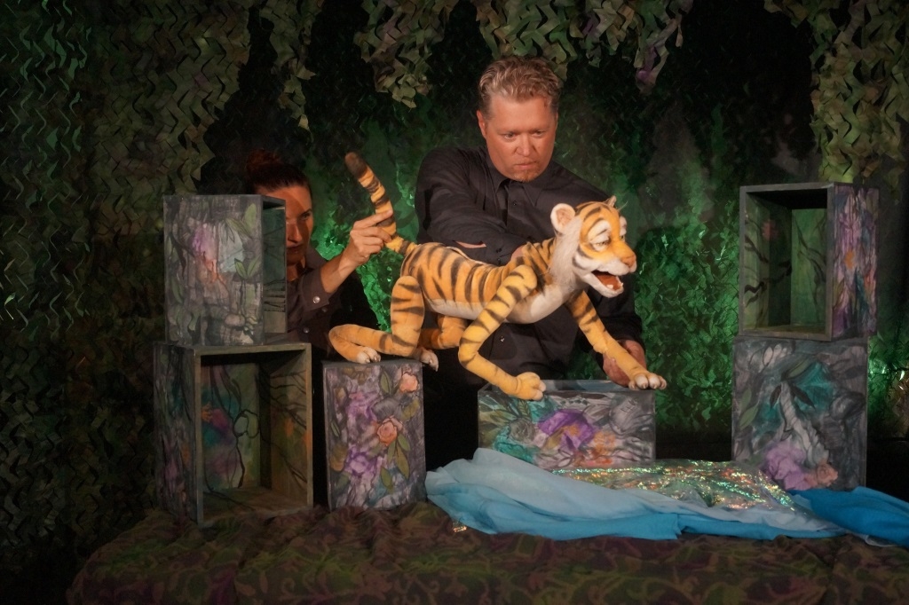 Mann mit Tigerfigur in Bühnenbild