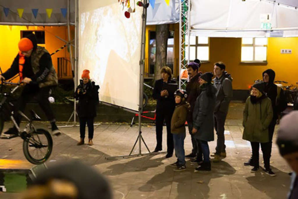 ein Fahrradfahrer führt etwas vor, einige Personen schauen zu