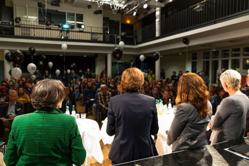 Foto aus dem Rücken der Podiumsteilnehmerinnen in Richtung Publikum