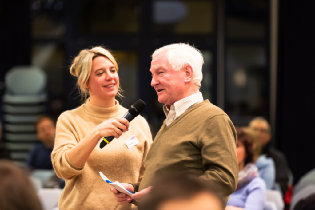 Ein Mann aus dem Publikum wird von der Moderatorin beim Stadtgespräch in Nippes interviewt.