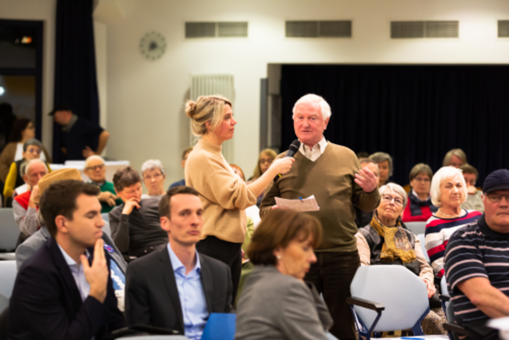 Ein Mann aus dem Publikum wird von der Moderatorin beim Stadtgespräch in Nippes interviewt.