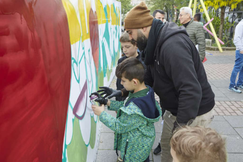 Der Graffiti-Künstler zeigt zwei Jungen den Umgang mit den Spraydosen