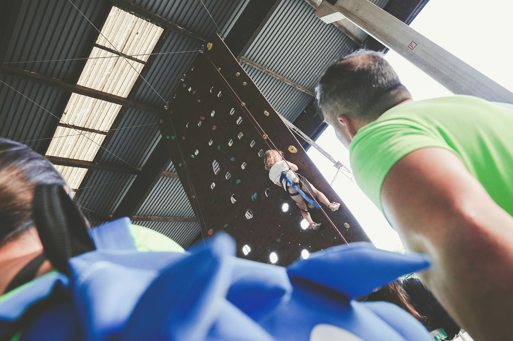 Aus der Froschperspektive ist ein Kind zu sehen, das am Hafentag eine Kletterwand nach oben klettert. 