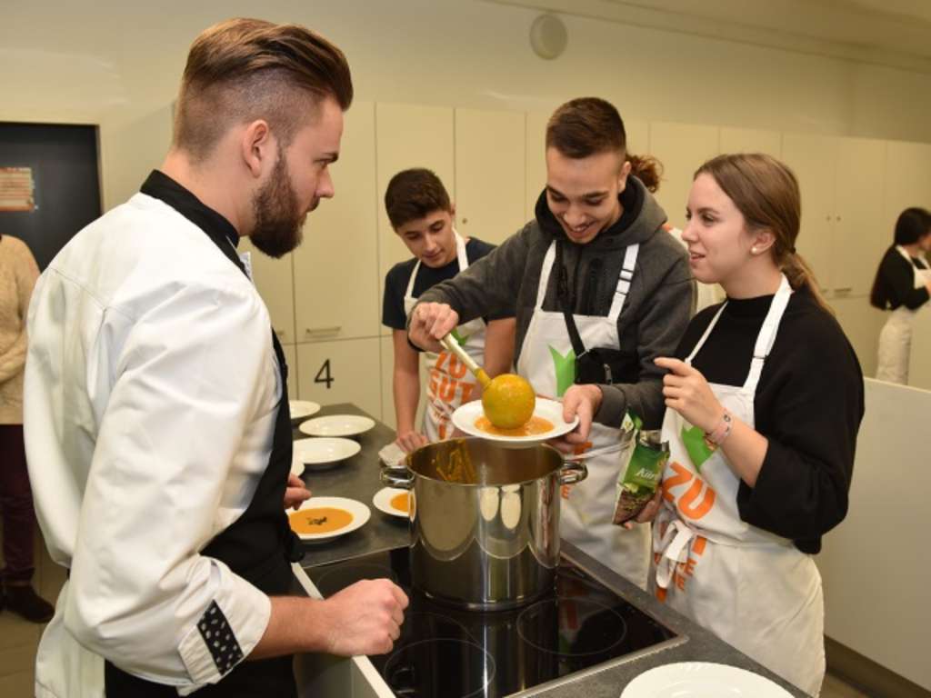 Jungkoch mit jugendlichen Kochkursteilnehmern