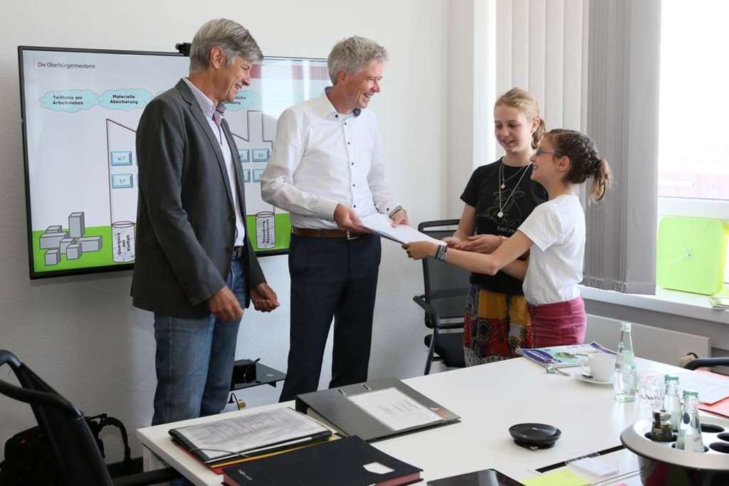 Zwei Schülerinnen des Leonardo-da-Vinci-Gymnasiums in Nippes übergeben eine Unterschriftenliste für mehr Ökostrom an Schulen an Umweltdezernent Dr. Harald Rau und Michael Nawroth von der Gebäudewirtschaft