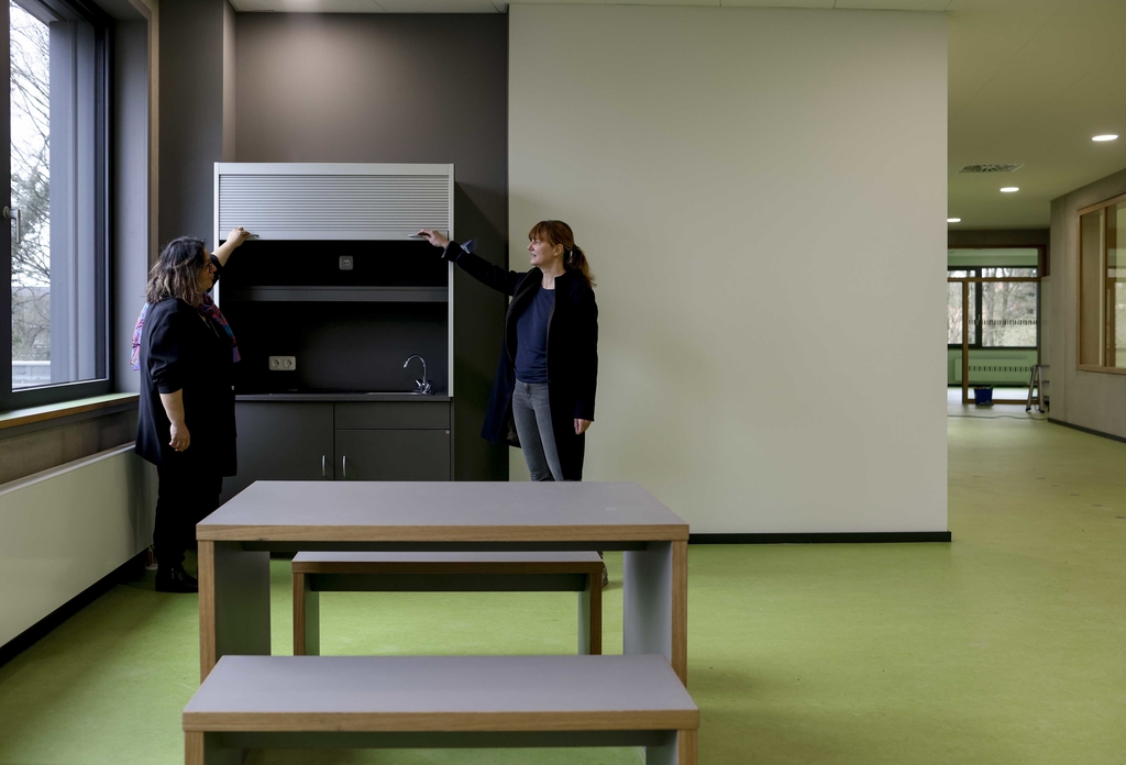 Grüne Bodenbeläge und kleine Teeküchen machen die Flure zu Zonen mit hoher Aufenthaltsqualität