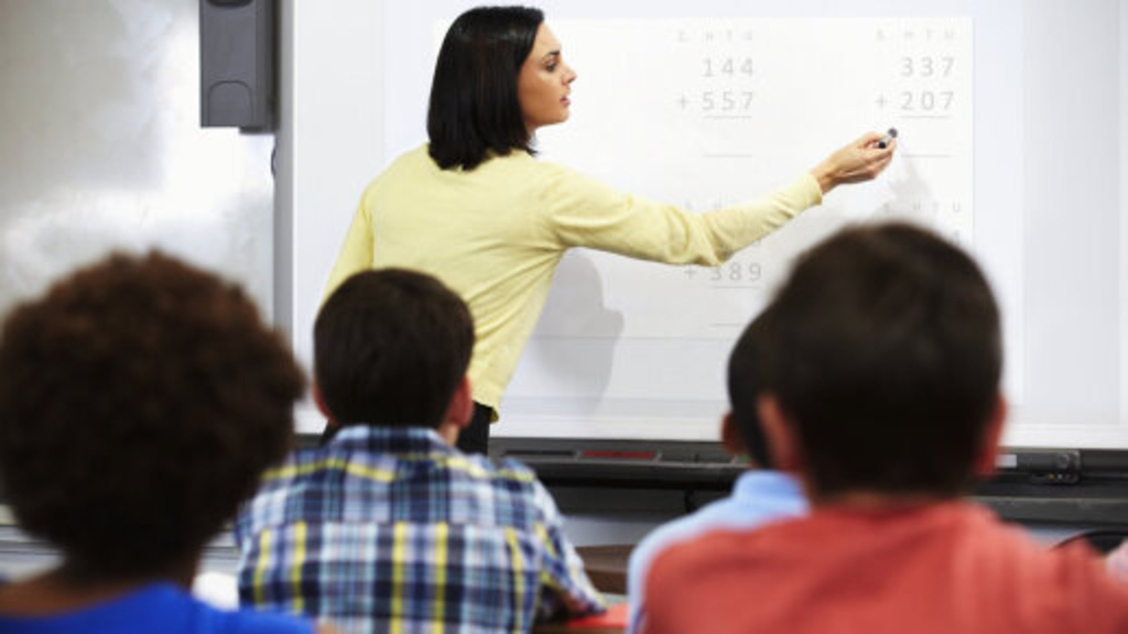 Lehrkraft erläutert Unterrichtsstoff an einem Whiteboard, Link auf Languages - KI Köln