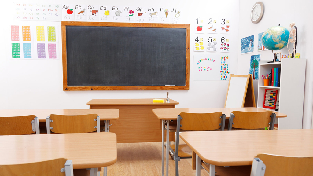 Klassenraum mit Tischen, Stühlen und einer Tafel