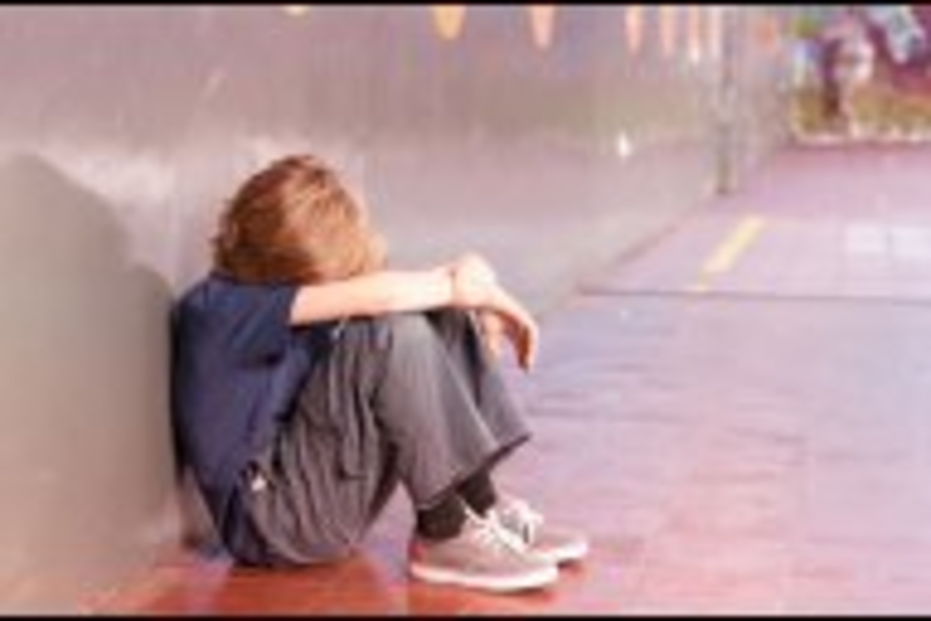 Junge sitzt kauernd auf dem Boden