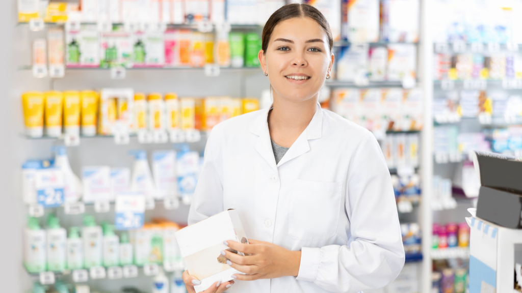 Junge Apothekerin hält ein Pharmazieprodukt in der Hand.
