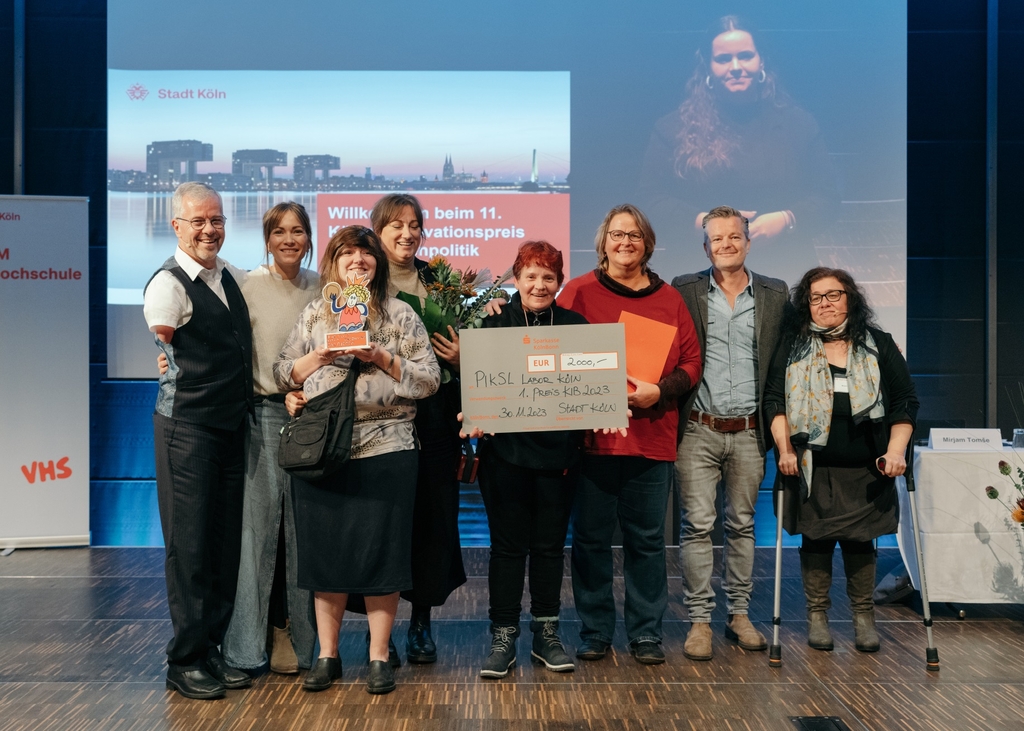 Vertreter*innen von PIKSL Labor Köln stehen auf einer Bühne und halten Scheck und Preis in der Hand.