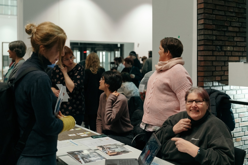 Infostand, um welchen mehrerer Personen stehen. 