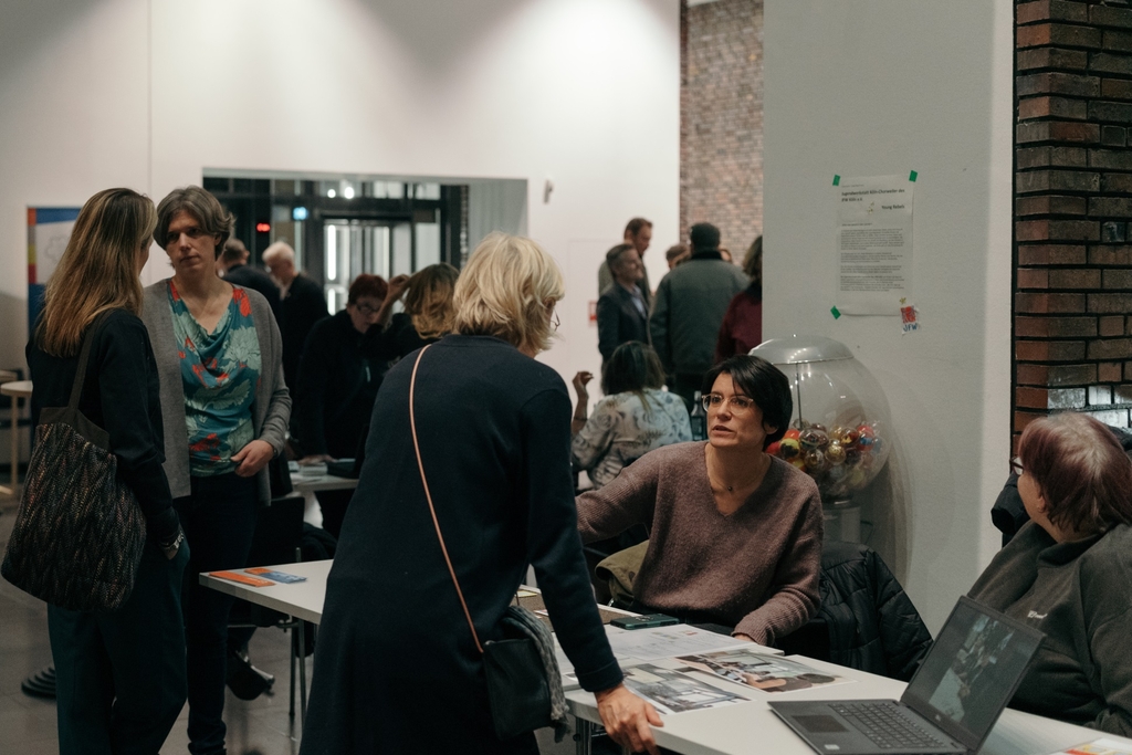 Infostand, um welchen verschiedene Personen stehen. 