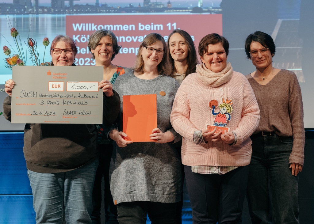 Vertreterinnen von SUSHI und KuBus e. V. halten Scheck und Preis in der Hand.