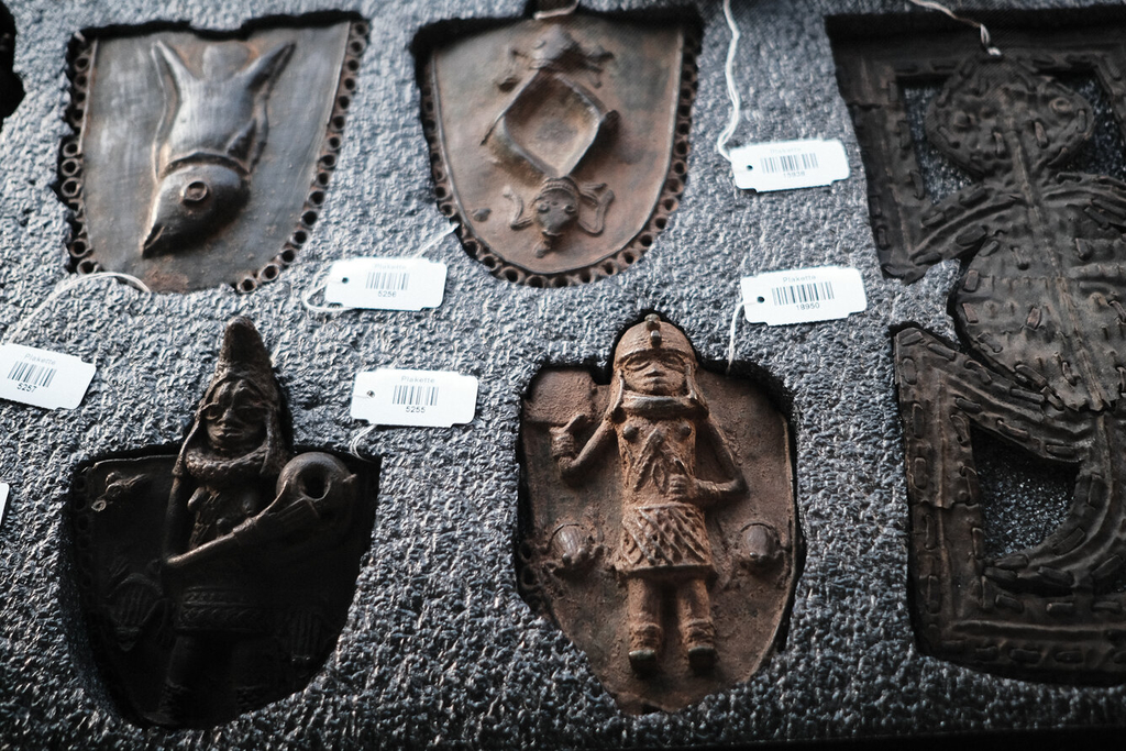 Mehrere Benin Bronzen liegen nebeneinander, menschliche und Tierfiguren sind zu erkennen