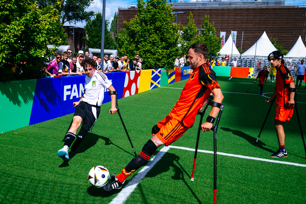 Foto von drei Mitspielern der Inklusionspielen, während sie Fußball spielen