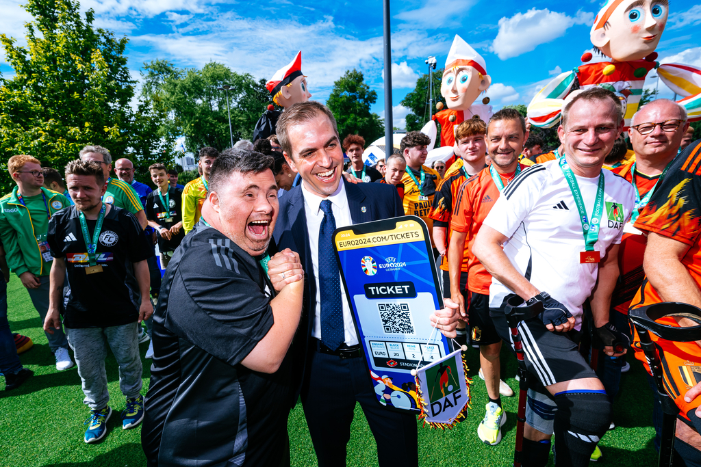 Foto von Philipp Lahm, der sich voller Freude die Hand mit einem Mann gibt
