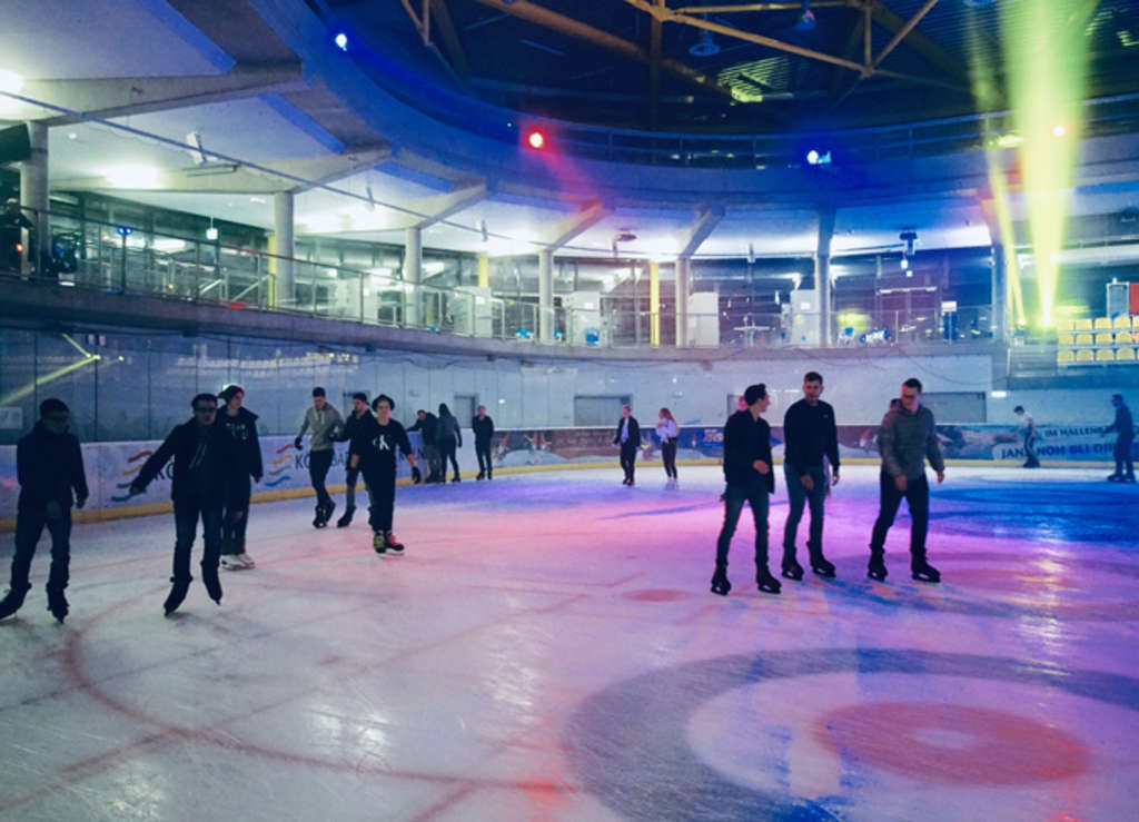 Schlittschuhläuferinnen und -läufer auf der Eisfläche. Bunte Dis