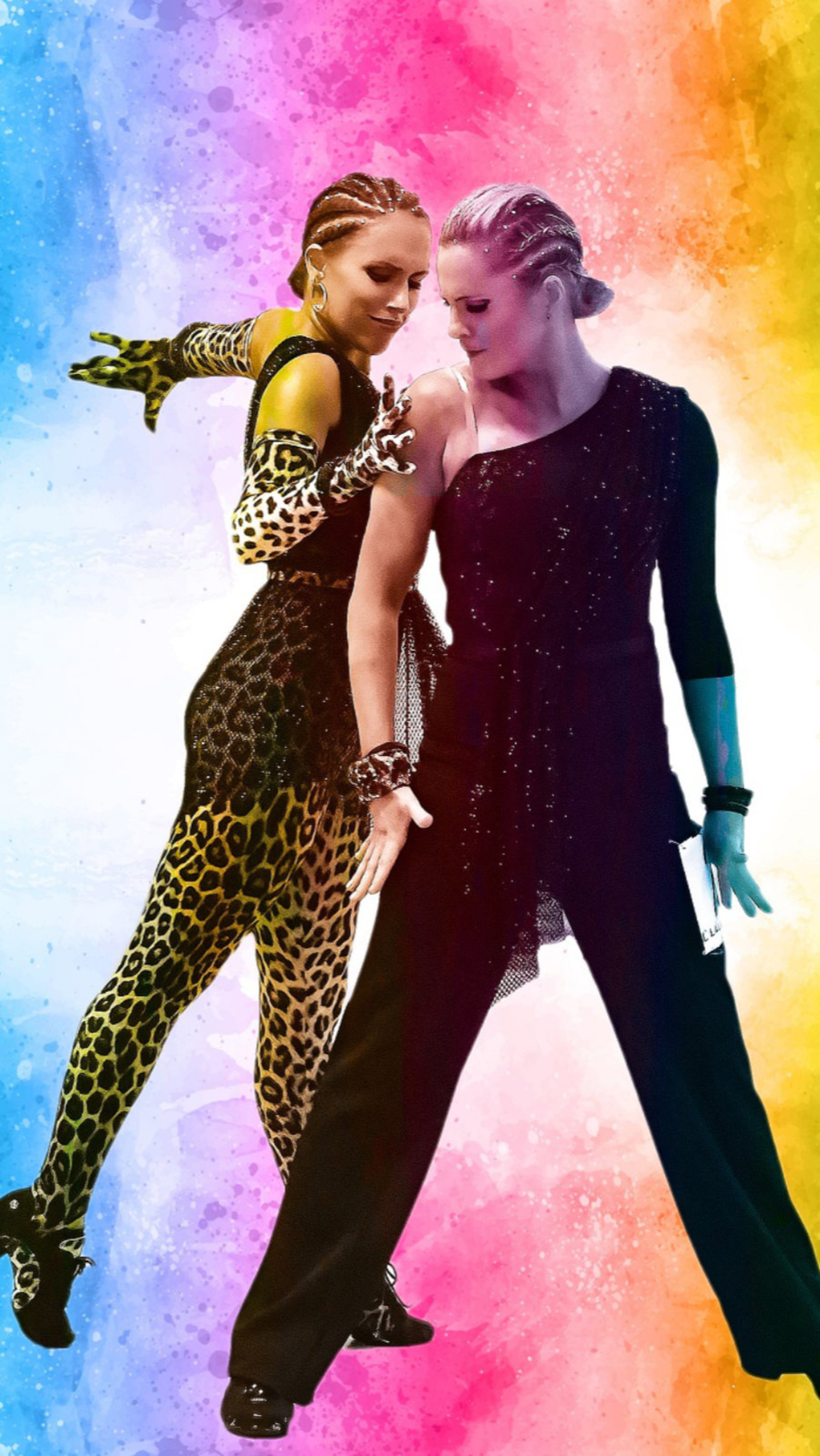 Zwei Tänzerinnen posieren vor buntem Hintergrund. Hierbei üben sie einen Tanzschritt aus.