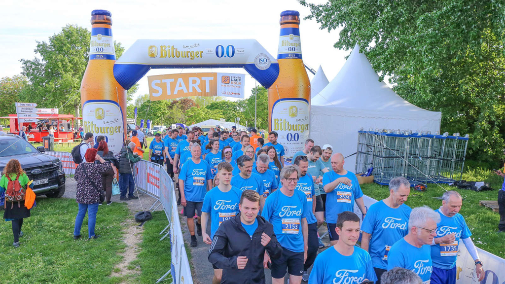 Das Foto zeigt einige Läufer*innen, welche durch den Startbogen