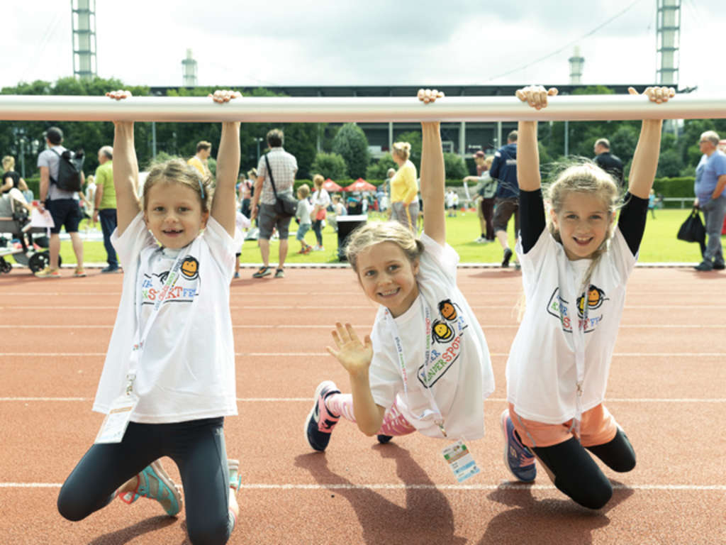 Drei Kinder beim KinderSportFest hängen am Geländer