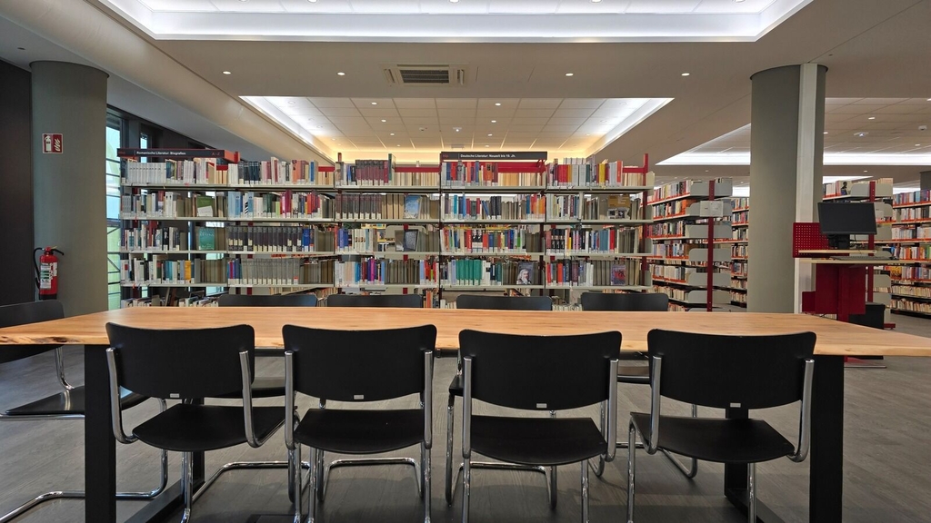 Ein langer Tisch mit Stühlen im Hintergrund Bücherregale