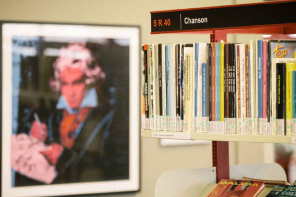 Notenregal, im Hintergrund ein Bild von Beethoven, Link auf Musikbibliothek - Stadt Köln
