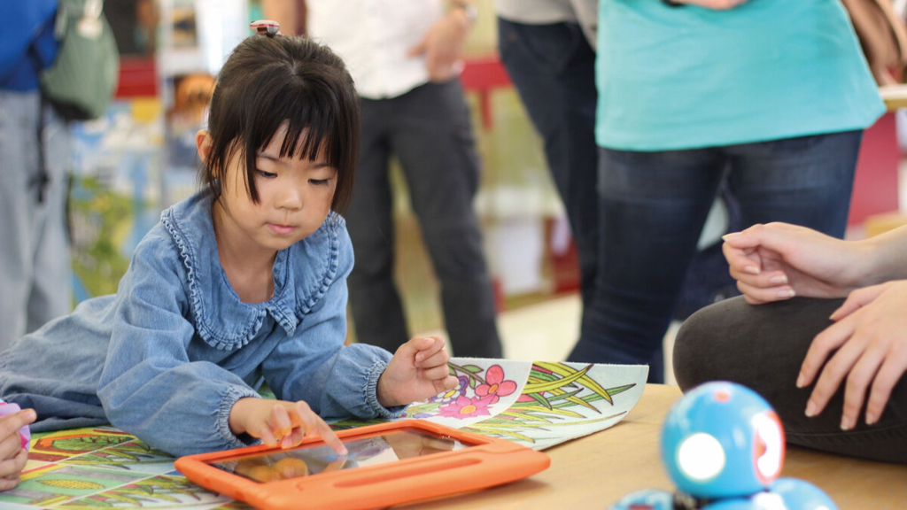 Mädchen spielt an einem Tisch mit einem iPad