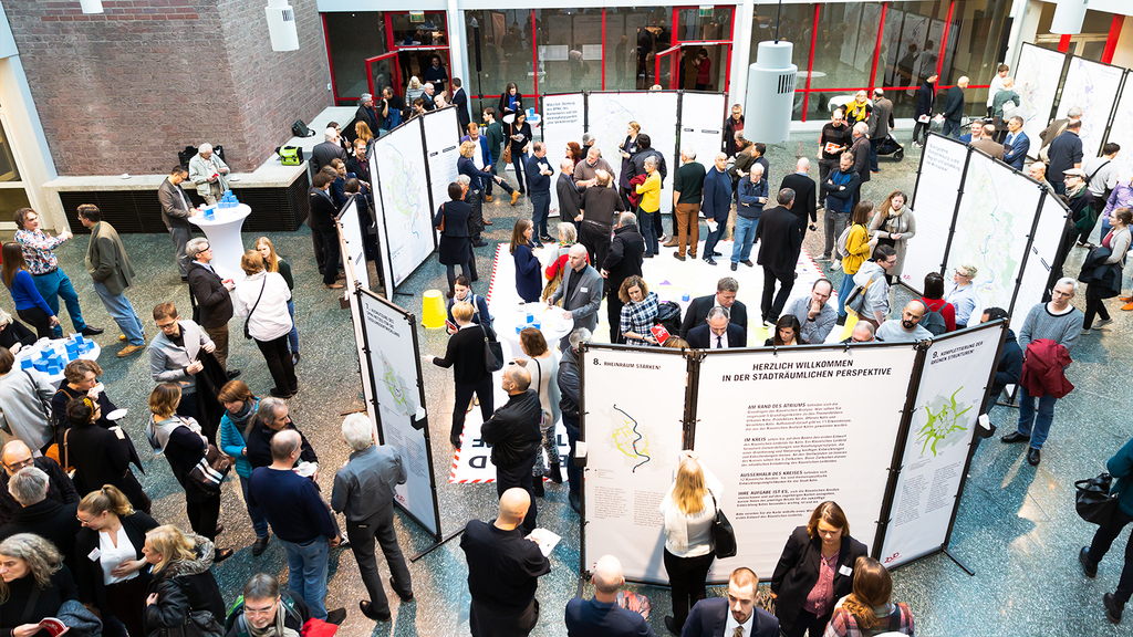 Das Foto zeigt eine Teilnehmende des zweiten Zukunftsforumsdie sich an verschiedenen Kartenaushängen informieren.