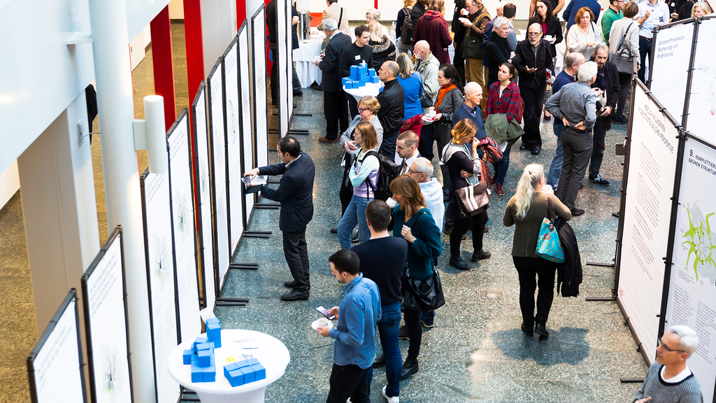 Das Foto zeigt Teilnehmende des zweiten Zukunftsforums, die sich an verschiedenen Kartenaushängen informieren.
