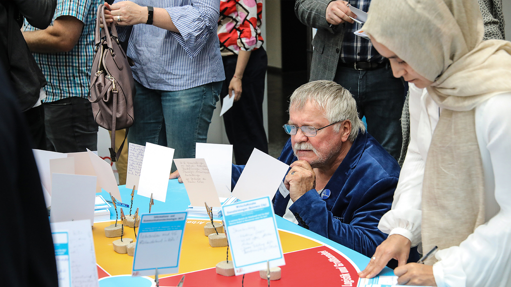 Das Foto zeigt Teilnehmende des ersten Zukunftsforums an einer Arbeitsstation.