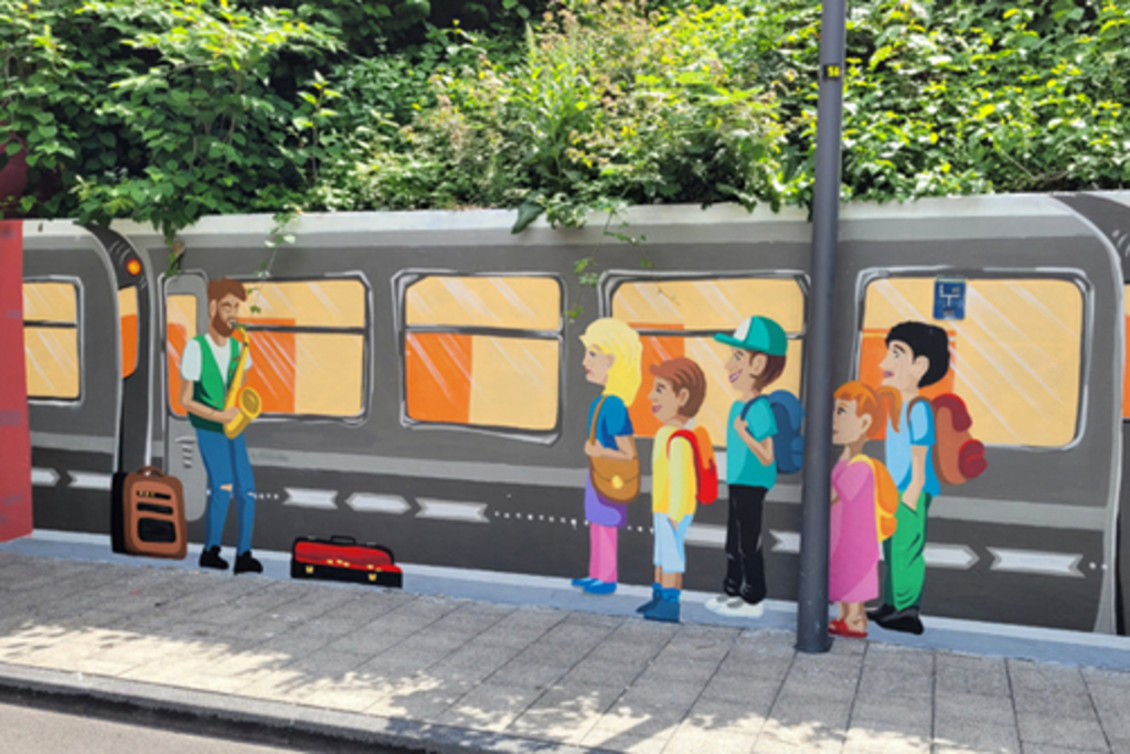 Illusionsmalerei in Unterführung Pingenweg Motiv „Bahnhof Lindweiler“: wartende Kinder mit Straßenmusikant